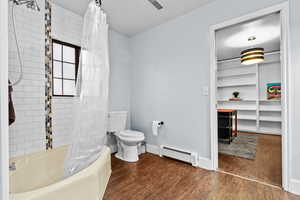 Bathroom with toilet, a baseboard radiator, shower / bathtub combination with curtain, and hardwood / wood-style floors