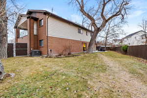 Rear view of property with a yard and central air condition unit