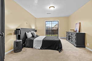 Carpeted bedroom featuring a baseboard radiator and a textured ceiling