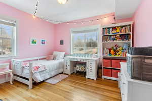 Bedroom with multiple windows, light hardwood / wood-style flooring, and rail lighting