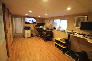 Office featuring a paneled ceiling, a barn door, and light hardwood / wood-style floors