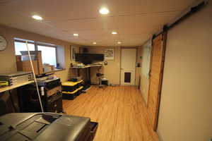 Interior space with a drop ceiling, light hardwood / wood-style flooring, and a barn door