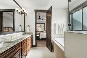 Bathroom featuring vanity, tiled bath, and a notable chandelier