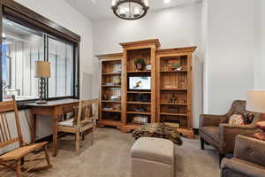 Office area with an inviting chandelier and light colored carpet