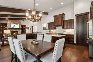 Dining space with a stone fireplace, sink, high vaulted ceiling, dark hardwood / wood-style floors, and beam ceiling