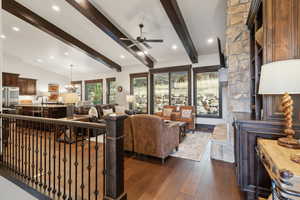 Living room featuring lofted ceiling with beams, dark hardwood / wood-style floors, and ceiling fan with notable chandelier