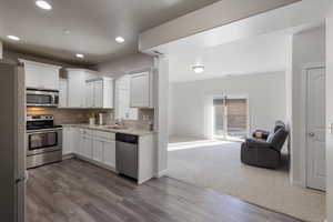 Kitchen with stainless steel appliances, dark hardwood / wood-style floors, sink, and white cabinets