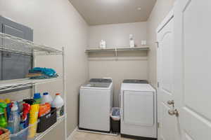 Laundry area with a textured ceiling, washer and dryer, and light tile patterned floors