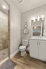 Bathroom with wood-type flooring, vanity, tiled shower, ceiling fan, and a textured ceiling