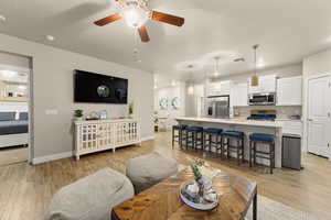 Living room featuring sink, light hardwood / wood-style flooring, a textured ceiling, and ceiling fan