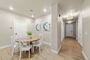 Dining space with a textured ceiling and light hardwood / wood-style flooring