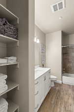 Full bathroom featuring tiled shower / bath, wood-type flooring, vanity, toilet, and a textured ceiling