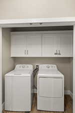 Laundry room with cabinets, hardwood / wood-style flooring, and washing machine and clothes dryer