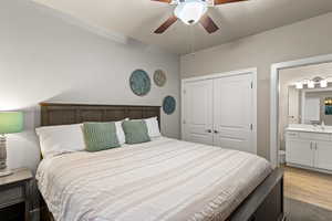 Bedroom featuring sink, ceiling fan, connected bathroom, a closet, and light wood-type flooring