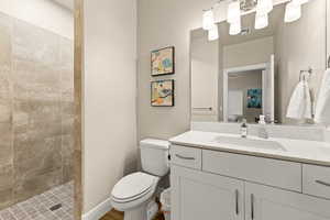 Bathroom featuring vanity, toilet, and a tile shower