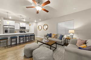 Living room featuring ceiling fan, sink, and light wood-type flooring