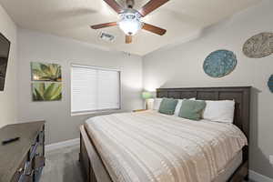 Bedroom featuring ceiling fan, carpet flooring, and a textured ceiling