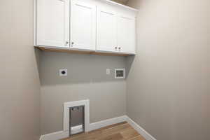 Washroom with cabinets, washer hookup, light hardwood / wood-style flooring, and electric dryer hookup