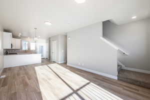 Unfurnished living room featuring sink, a notable chandelier, and light hardwood / wood-style flooring