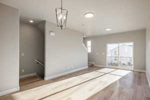 Unfurnished living room with a notable chandelier and light wood-type flooring