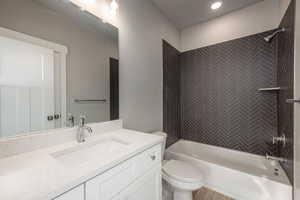 Full bathroom featuring tiled shower / bath combo, vanity, and toilet