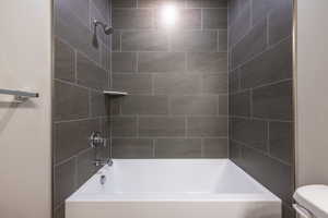 Bathroom with tiled shower / bath and toilet