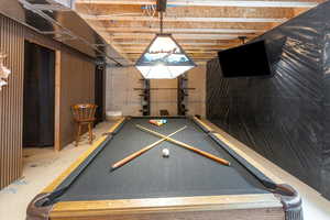 Recreation room featuring pool table, concrete floors, and wood walls