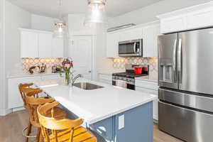 Kitchen featuring white cabinetry, sink, a center island with sink, and appliances with stainless steel finishes