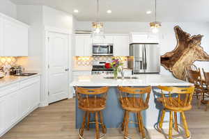 Kitchen with pendant lighting, white cabinets, and appliances with stainless steel finishes