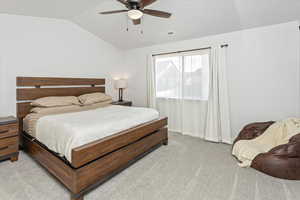 Carpeted bedroom with vaulted ceiling and ceiling fan