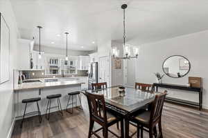 Dining room featuring sink, a notable chandelier, and dark wood-type flooring