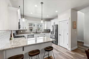 Kitchen featuring sink, hanging light fixtures, appliances with stainless steel finishes, kitchen peninsula, and white cabinets