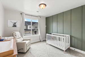 Carpeted bedroom featuring a crib