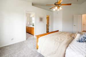 Carpeted bedroom featuring ensuite bath, ceiling fan, and a spacious closet