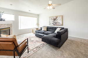 Carpeted living room with ceiling fan, lofted ceiling, and a tiled fireplace