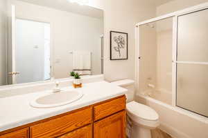 Full bathroom featuring bath / shower combo with glass door, vanity, and toilet