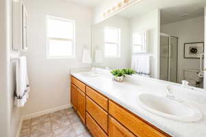 Bathroom featuring vanity, a wealth of natural light, a shower with shower door, and toilet