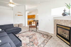 Living room featuring light carpet, a tile fireplace, and ceiling fan