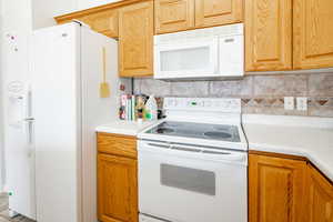 Kitchen featuring backsplash and white appliances