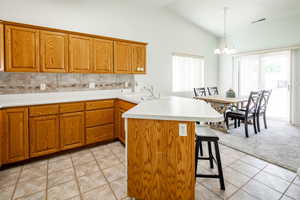 Kitchen featuring lofted ceiling, a breakfast bar, sink, decorative light fixtures, and light carpet