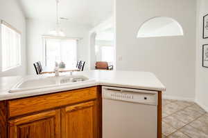 Kitchen featuring white dishwasher, sink, hanging light fixtures, and a chandelier