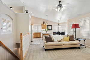 Carpeted living room featuring ceiling fan with  high vaulted ceiling