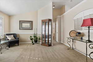 Sitting room with lofted ceiling, a healthy amount of sunlight, and light carpet