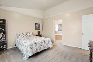 Bedroom featuring crown molding, vaulted ceiling, carpet floors, and ensuite bath