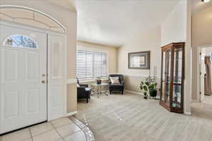 Carpeted entryway featuring lofted ceiling and a textured ceiling