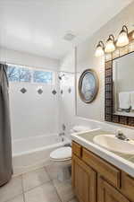 Full bathroom with tile patterned floors, toilet, a textured ceiling, vanity, and shower / bath combo