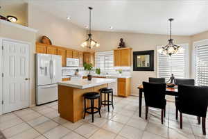 Kitchen featuring white appliances, decorative light fixtures, a center island, and light tile patterned flooring