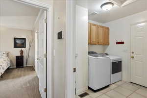 Washroom with cabinets, washer and dryer, and light tile patterned floors