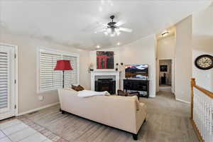 Living room with lofted ceiling, light tile patterned floors, and ceiling fan