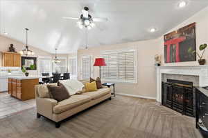 Tiled living room featuring a fireplace, ceiling fan and vaulted ceiling